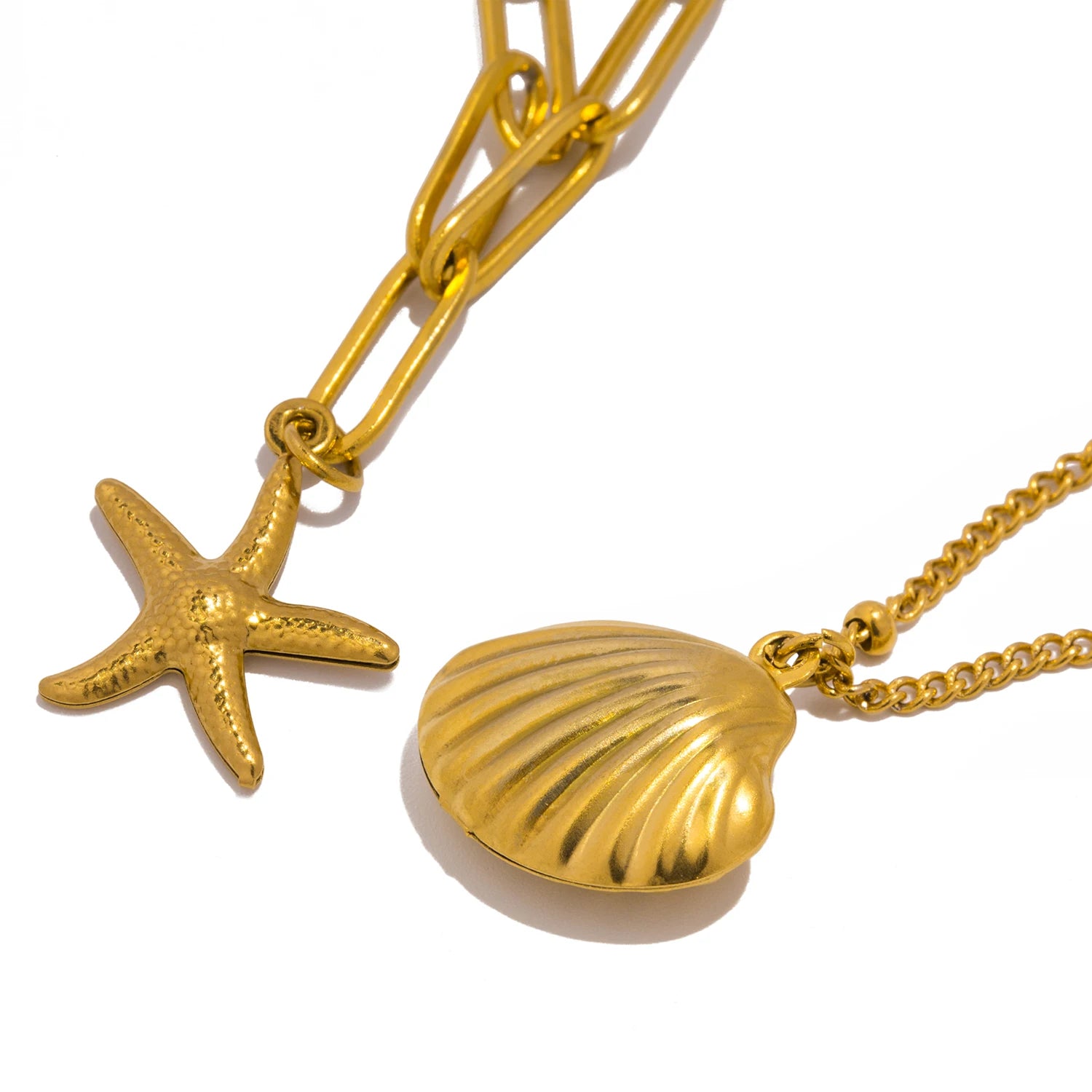 Close-up of a gold layered necklace featuring a textured seashell pendant and a starfish charm, photographed on a clean white background. Trendy beach-themed jewelry.