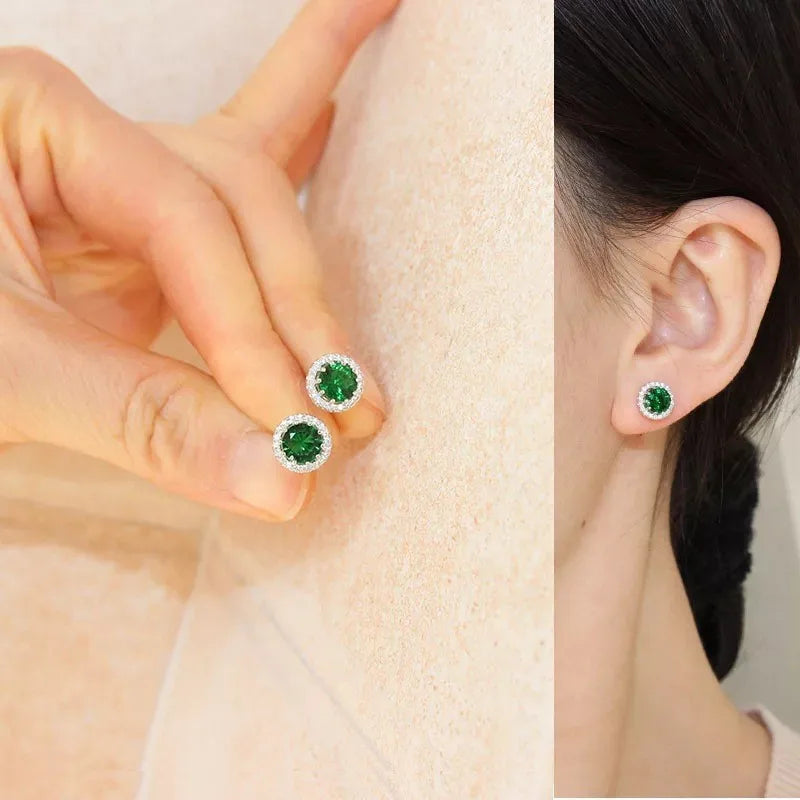 A pair of elegant round stud earrings featuring a vibrant green gemstone surrounded by a halo of sparkling stones, shown in a split image with one view held in a hand and the other worn on a model's ear.